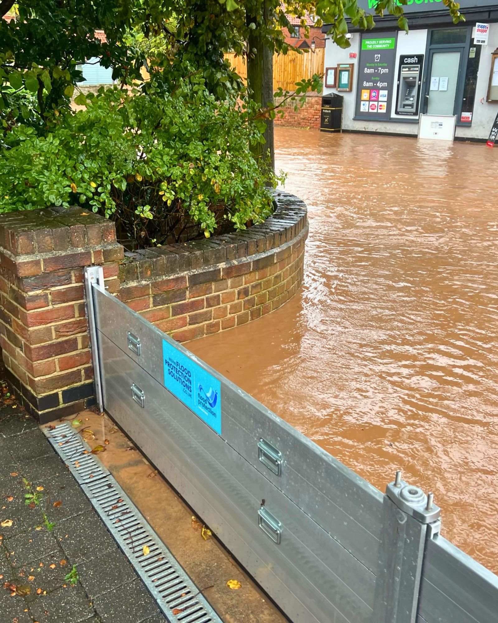 A Flood Protection Solutions flood barrier holding back floodwater outside a shop
